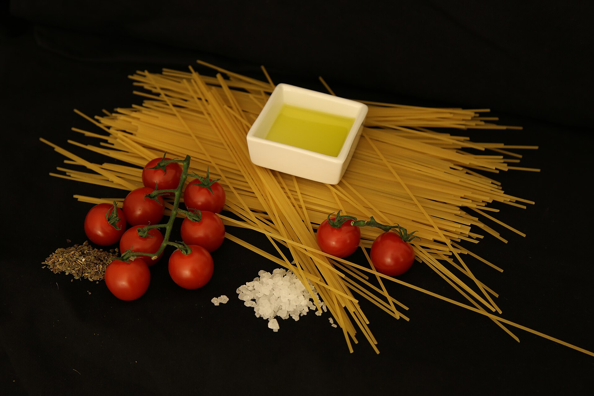 마른 스파게티 면과 방울토마토, 올리브유 한 종지, 굵은소금을 늘어놓은 모습
